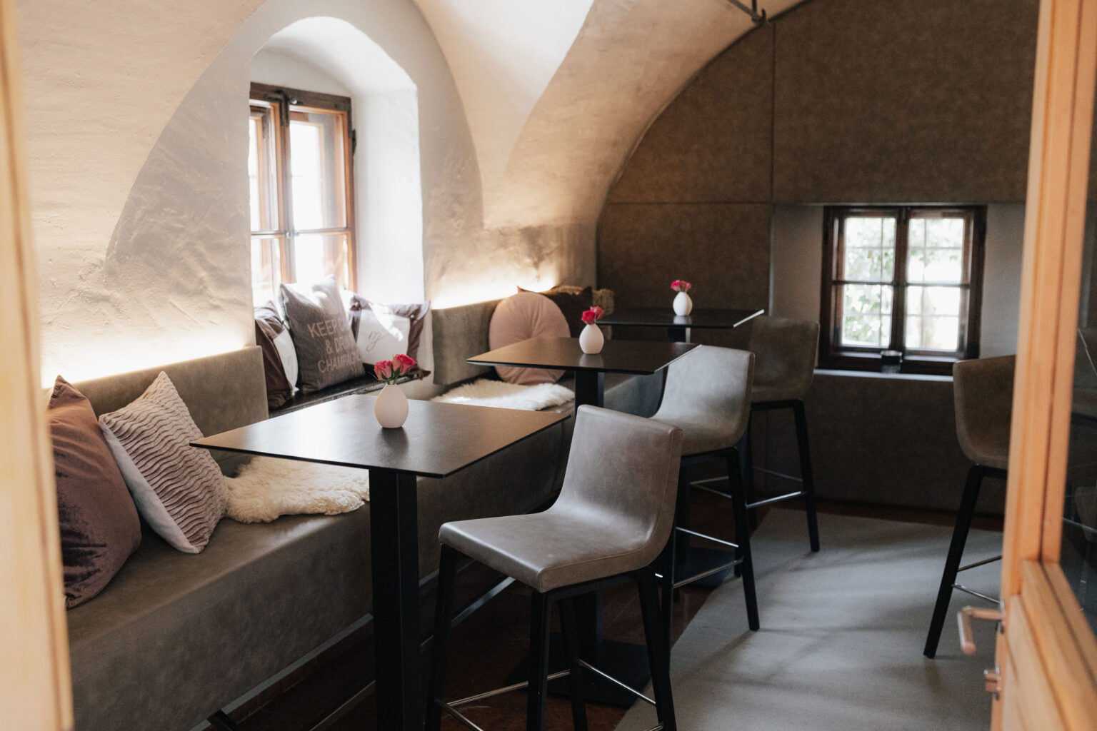 Barbereich im Mesnerhaus mit Gew&ouml;lbedecke, Sitzb&auml;nken und hohen Tischen