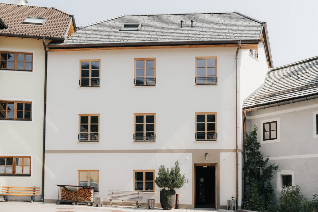 mesnerhaus-boutique-hotel-aussen-01 Frontansicht des Mesnerhaus Boutique-Hotels mit weißer Fassade und Holzkastenfenstern