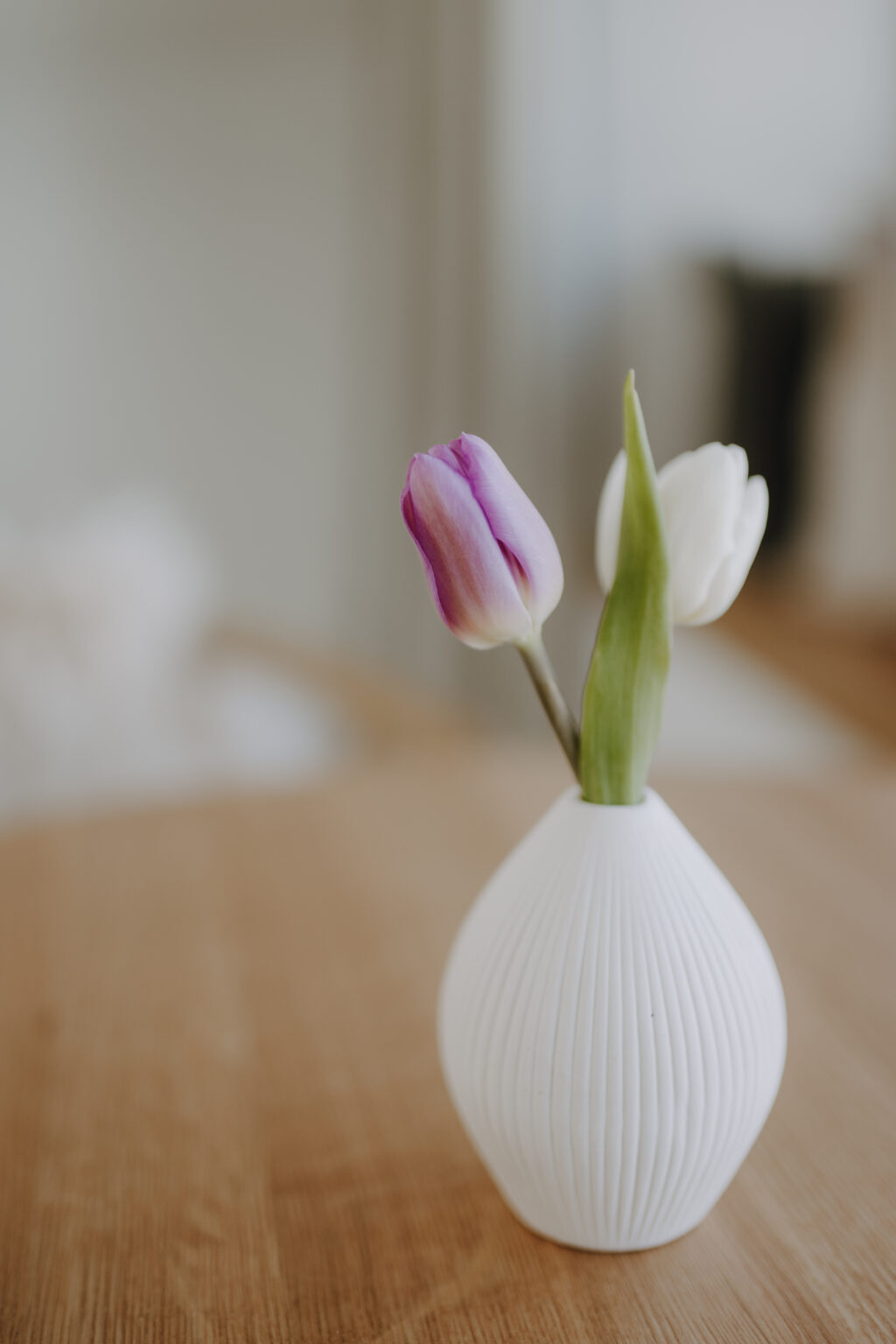Kleine Vase mit zwei Tulpen auf einem Holztisch im Mesnerhaus