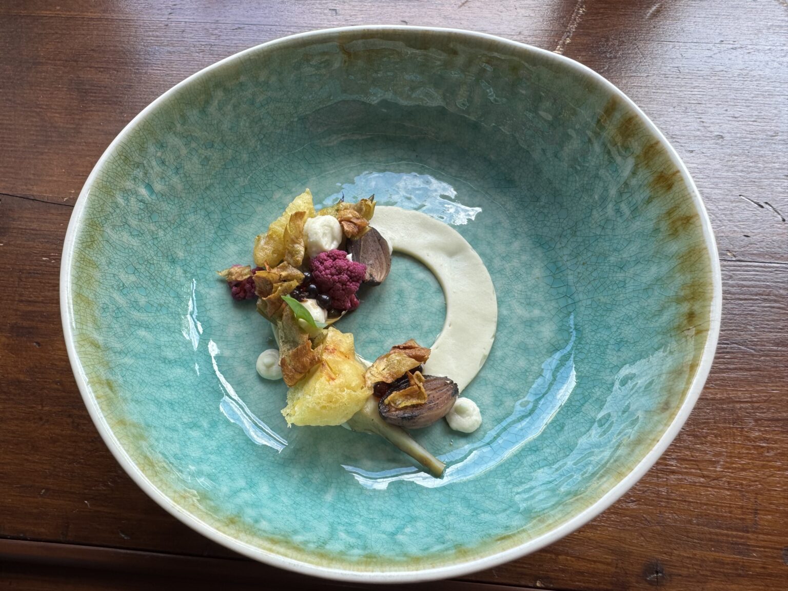 Gericht mit Marchfelder Artischocke, Bl&uuml;ten und heller Creme in einer t&uuml;rkisfarbenen Schale