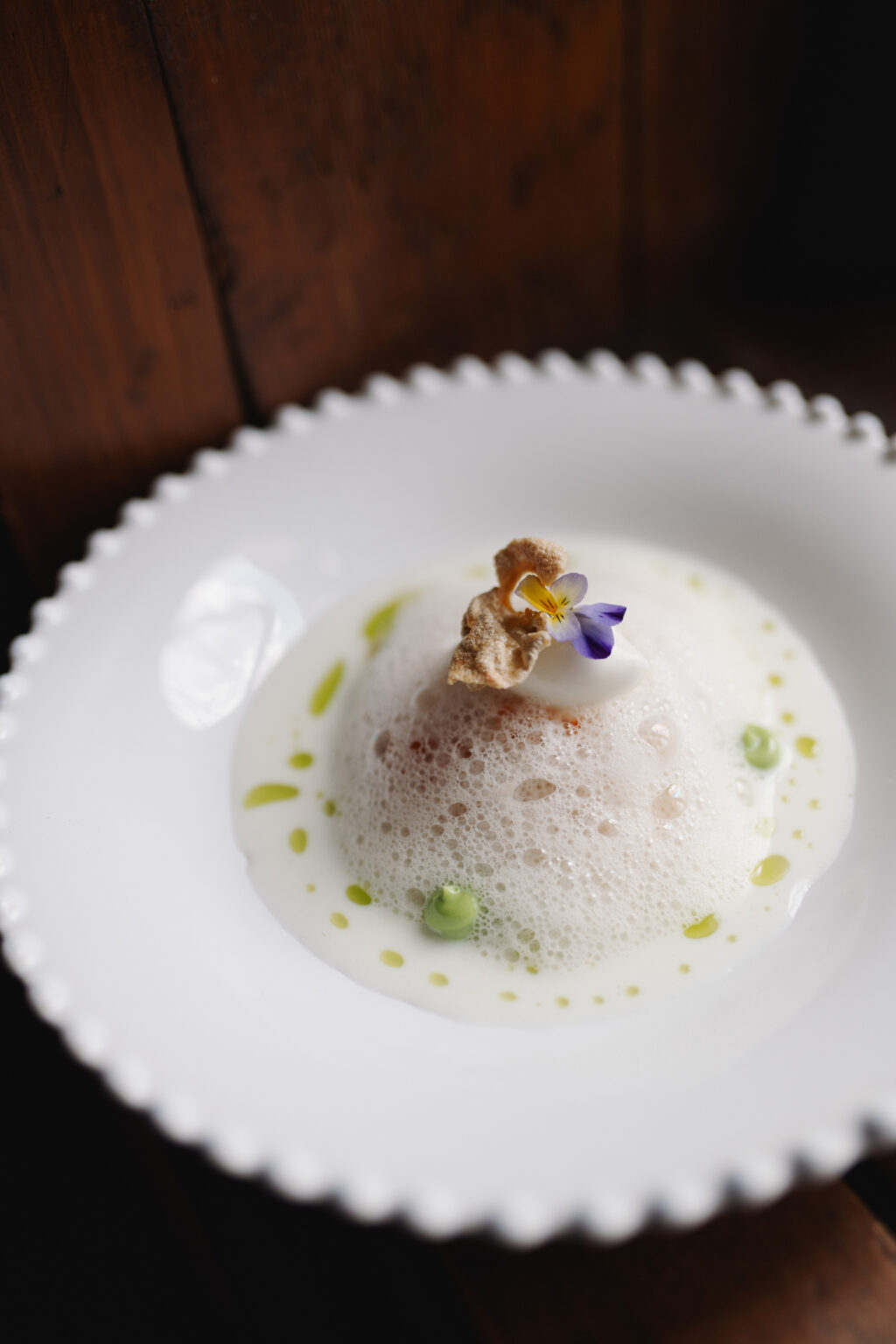 Kuppelf&ouml;rmig angerichtetes Gericht in heller Sauce mit Bl&uuml;te und Kr&auml;uter&ouml;l