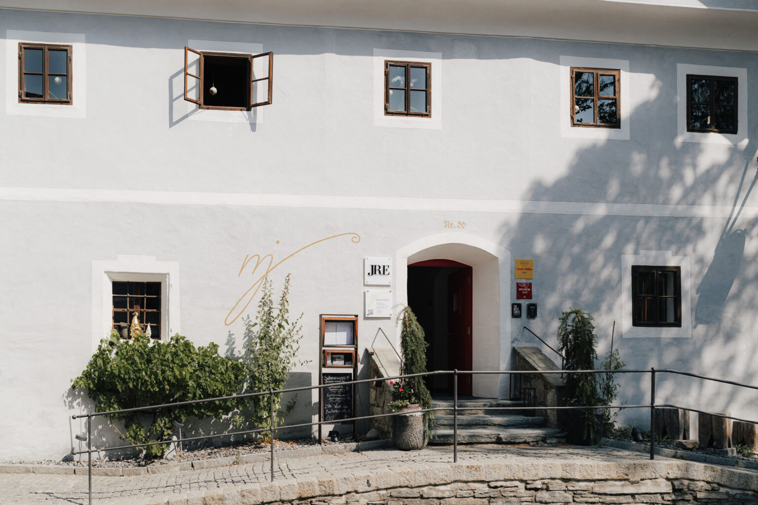 Wei&szlig;e Fassade des Mesnerhaus Gourmet-Restaurants mit Eingang und Terrasse