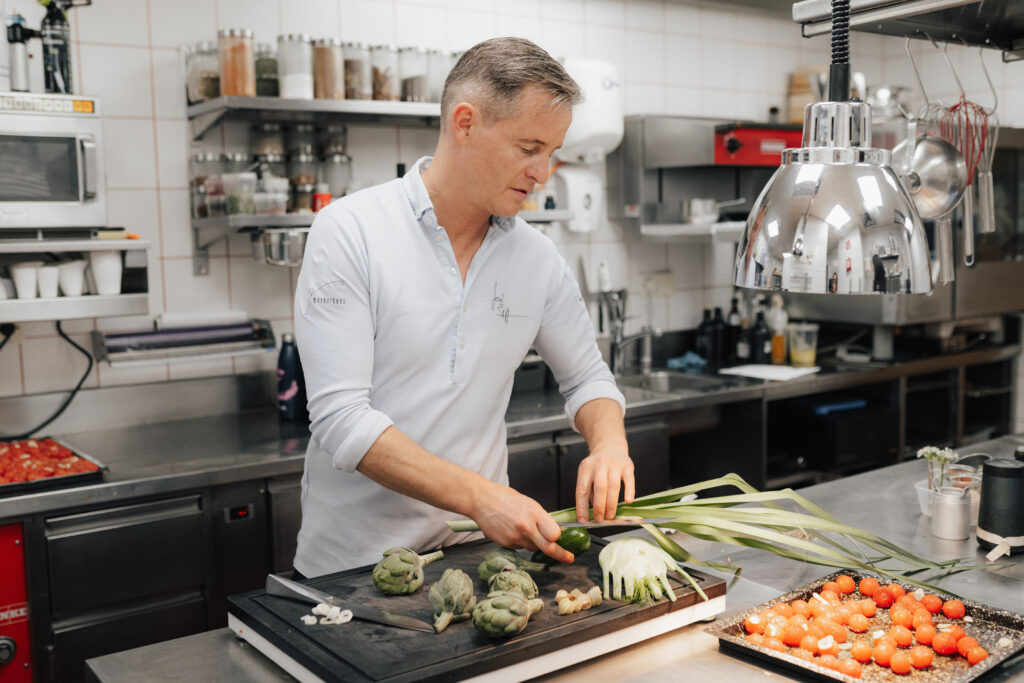 mesnerhaus-josef-steffner-beim-anrichten Josef Steffner beim Vorbereiten von Artischocken, Fenchel und Tomaten in der Restaurantküche