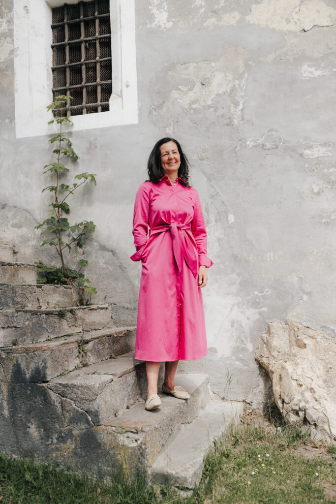 mesnerhaus-maria-steffner-05 Maria Steffner in einem pinkfarbenen Kleid vor einer historischen Steinwand