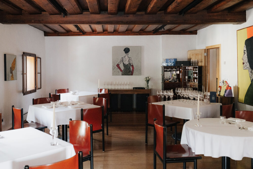 mesnerhaus-restaurant-01 Gastraum des Mesnerhaus Gourmet-Restaurants mit weißen Tischtüchern, roten Stühlen und Holzbalkendecke