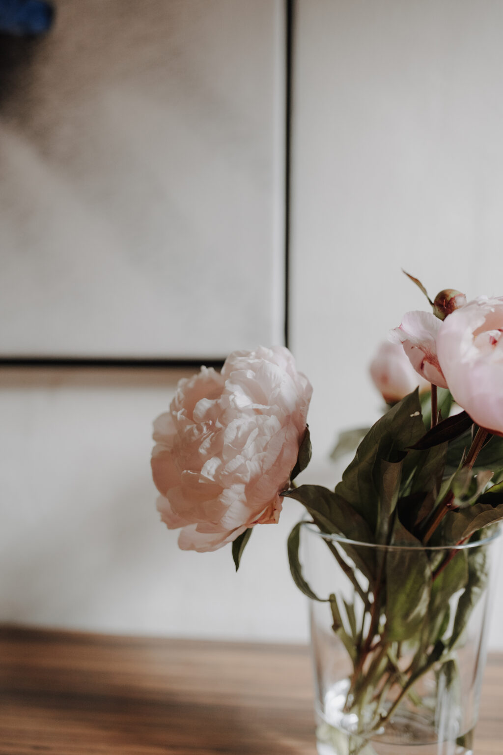 Rosa Pfingstrosen in einer Glasvase vor einem Kunstwerk im Mesnerhaus Gourmet-Restaurant