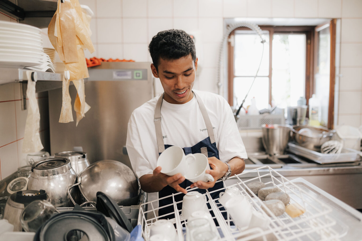 Steward Aagnima Sherpa beim Einr&auml;umen von Geschirr in der Restaurantk&uuml;che