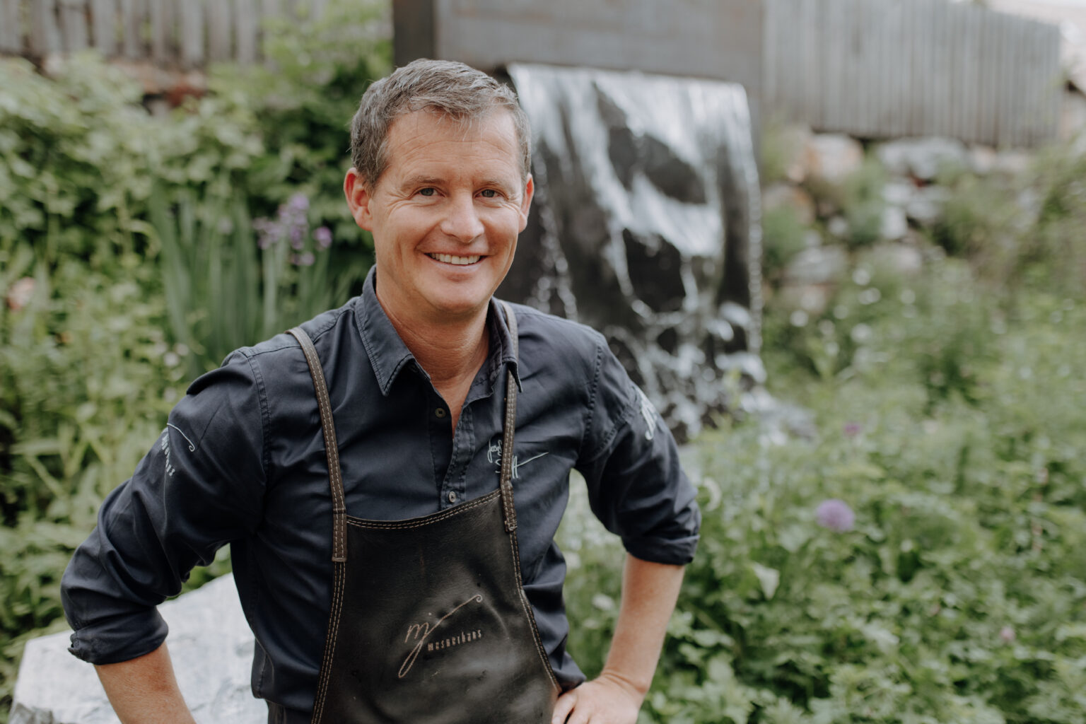 Josef Steffner mit Sch&uuml;rze im Garten des Mesnerhauses