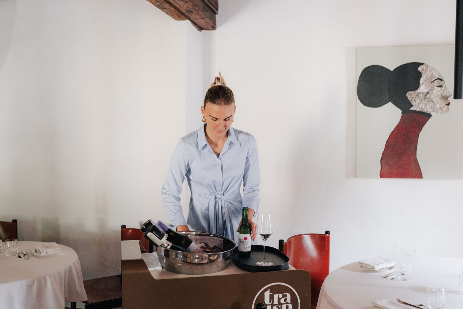 Restaurantfachfrau-Lehrling Lisa Erber an einem Servierwagen mit Wein und Sektk&uuml;hlern