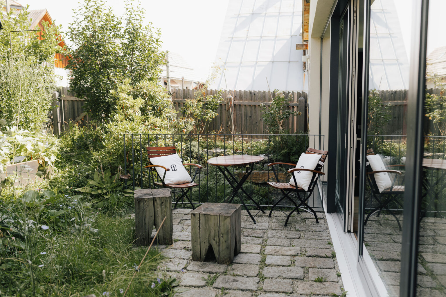 Untere Gartenterrasse des Mesnerhauses mit Tischen, St&uuml;hlen und Gr&uuml;npflanzen