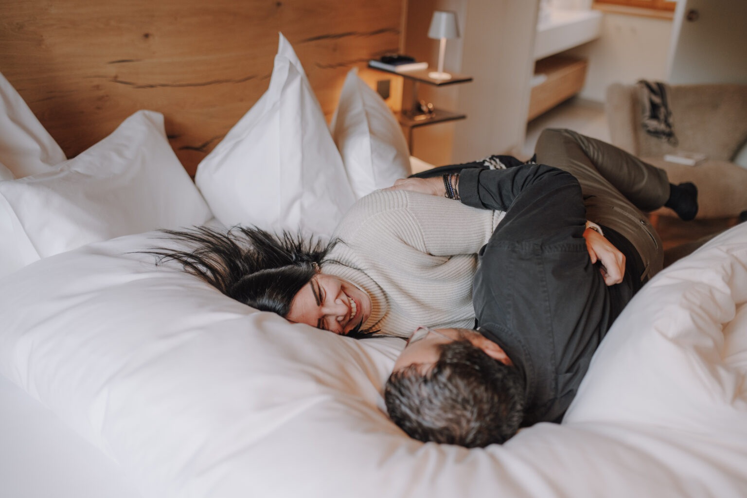 Lachendes Paar auf einem Doppelbett im Mesnerhaus Boutique-Hotel
