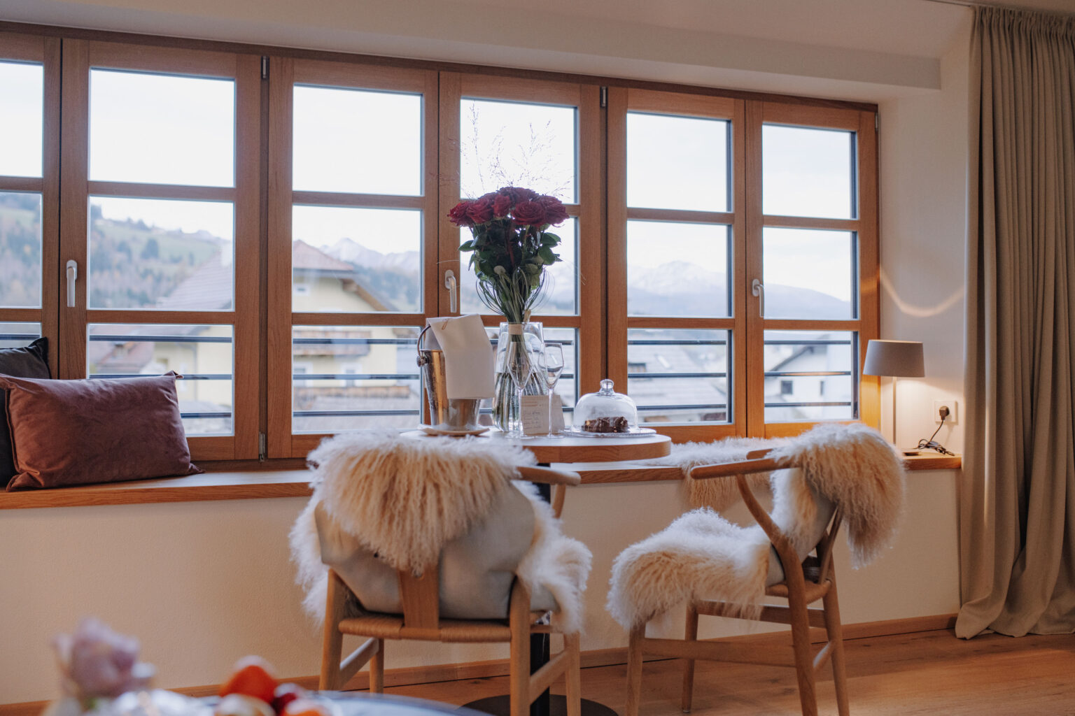 Sitzplatz am Panoramafenster im Mesnerhaus Boutique-Hotel mit Blumen, Wein und Bergblick
